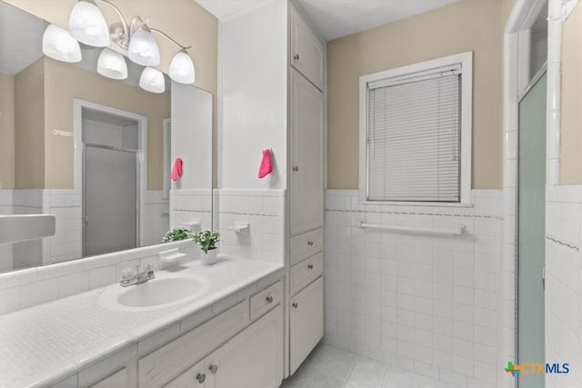 bathroom with vanity, tile walls, an enclosed shower, and a wainscoted wall