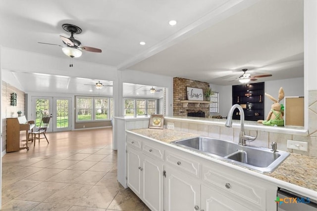 kitchen with a brick fireplace, a ceiling fan, open floor plan, and a sink