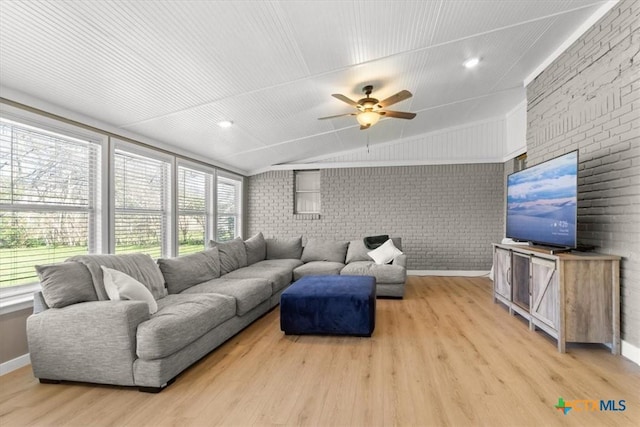 living area with light wood finished floors, brick wall, baseboards, ceiling fan, and lofted ceiling