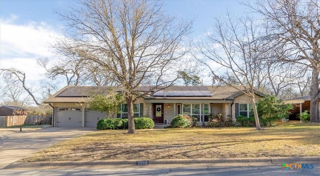 single story home with roof mounted solar panels, concrete driveway, a garage, and fence