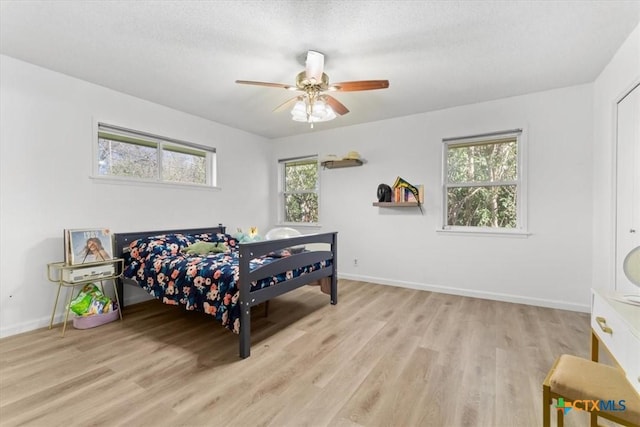 bedroom with multiple windows, ceiling fan, baseboards, and wood finished floors