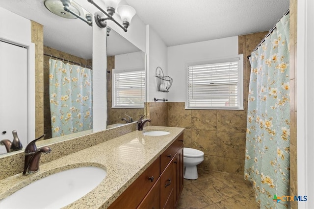 full bathroom with a sink, a wainscoted wall, toilet, and tile walls