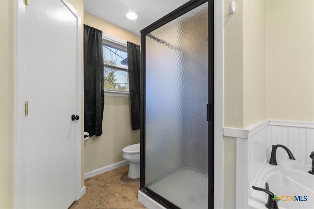 bathroom featuring a bath, a wainscoted wall, a shower stall, and toilet