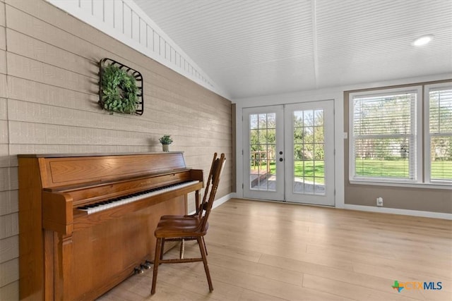 interior space with french doors, baseboards, light wood-style floors, and vaulted ceiling