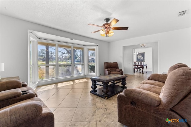 living room with visible vents, a ceiling fan, a textured ceiling, light tile patterned flooring, and baseboards