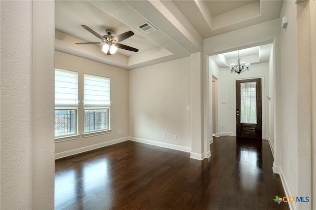 entrance foyer with ceiling fan with notable chandelier, dark hardwood / wood-style flooring, and a tray ceiling