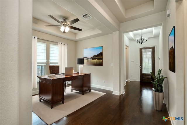 office area with ceiling fan with notable chandelier, dark wood-type flooring, and a tray ceiling