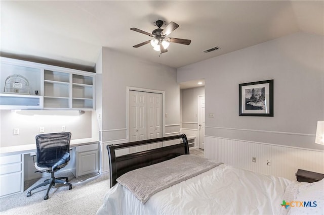 bedroom with ceiling fan, a closet, built in desk, and light carpet