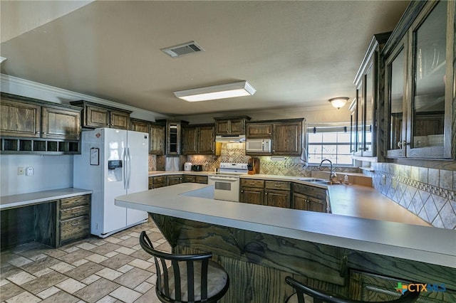 kitchen with sink, tasteful backsplash, ornamental molding, kitchen peninsula, and white appliances