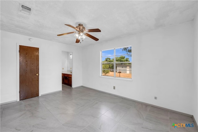 empty room with ceiling fan and a textured ceiling