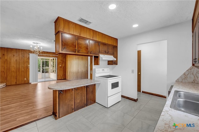 kitchen featuring wood walls, an inviting chandelier, range with electric cooktop, and a textured ceiling