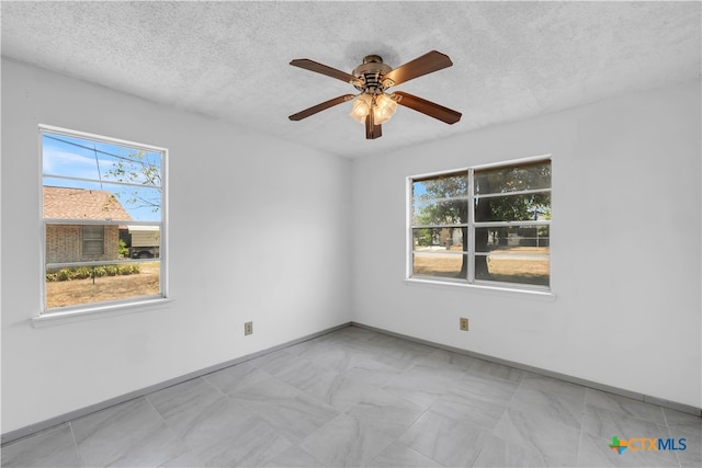 spare room with a wealth of natural light, a textured ceiling, and ceiling fan