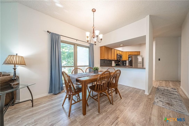 401 W Lincoln St Unit A201, New Braunfels, TX 78130 - dining room featuring a chandelier, light wood-style floors, a textured ceiling, and baseboards