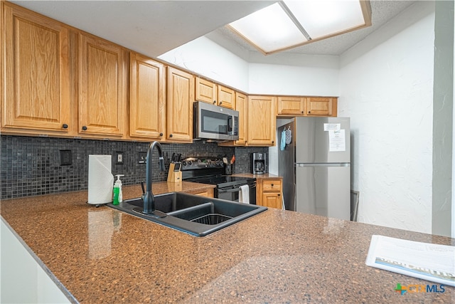 kitchen with sink, kitchen peninsula, appliances with stainless steel finishes, tasteful backsplash, and stone counters