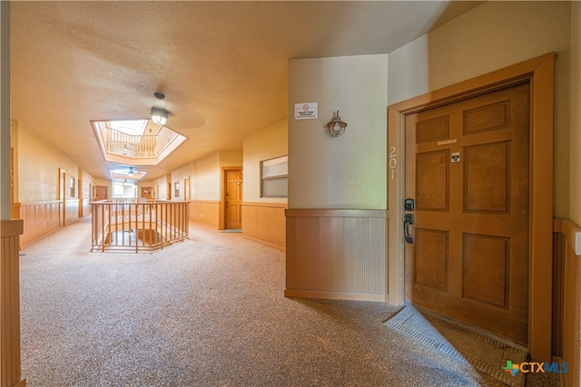 bonus room featuring wooden walls, a skylight, a textured ceiling, and carpet floors