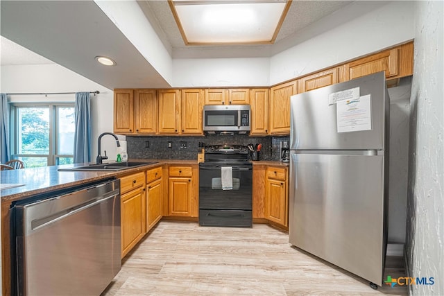 kitchen featuring stainless steel appliances, sink, backsplash, and light hardwood / wood-style flooring