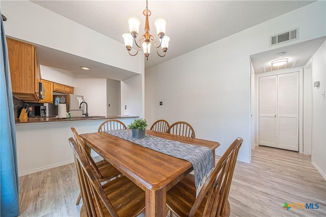 401 W Lincoln St Unit A201, New Braunfels, TX 78130 - dining area featuring a chandelier, light wood finished floors, baseboards, and a textured ceiling