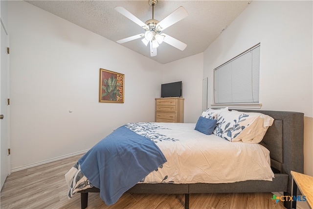 bedroom with hardwood / wood-style flooring, a textured ceiling, and ceiling fan