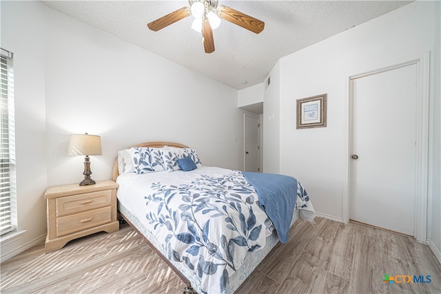 bedroom with a textured ceiling, light hardwood / wood-style floors, and ceiling fan