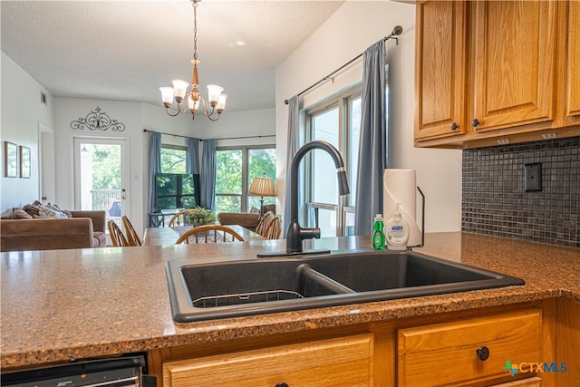 kitchen with sink, a textured ceiling, hanging light fixtures, a notable chandelier, and decorative backsplash