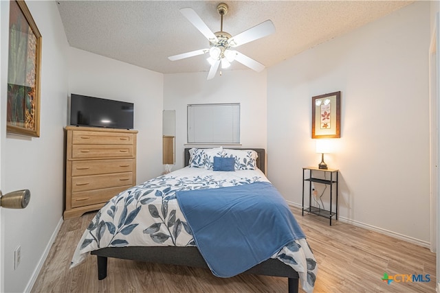 bedroom featuring ceiling fan, a textured ceiling, and light hardwood / wood-style flooring