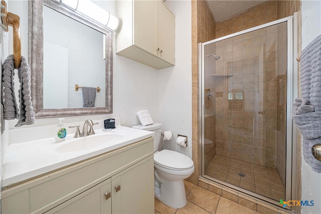 bathroom featuring vanity, a shower with door, tile patterned flooring, and toilet