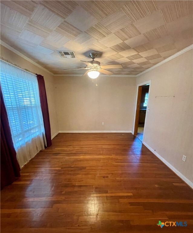 spare room featuring ornamental molding, dark wood-type flooring, and ceiling fan