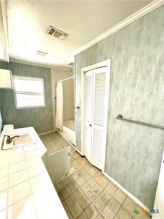 bathroom with sink, crown molding, and shower / bathtub combination with curtain