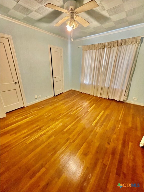 unfurnished room featuring ceiling fan, wood-type flooring, and ornamental molding