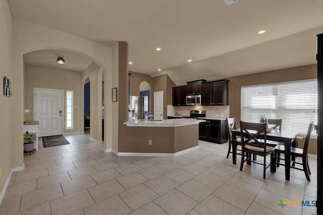 kitchen featuring sink, light tile patterned floors, light stone counters, dark brown cabinetry, and stainless steel appliances