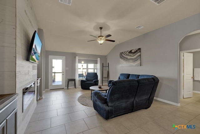 tiled living room with ceiling fan, a fireplace, and vaulted ceiling