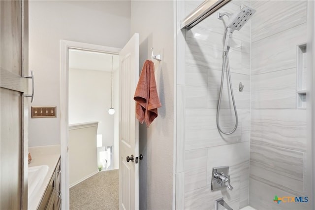 bathroom with a tile shower and vanity