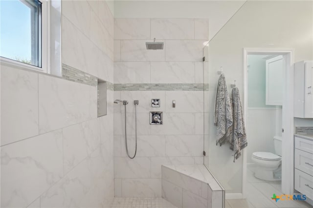 bathroom with a tile shower, vanity, and toilet