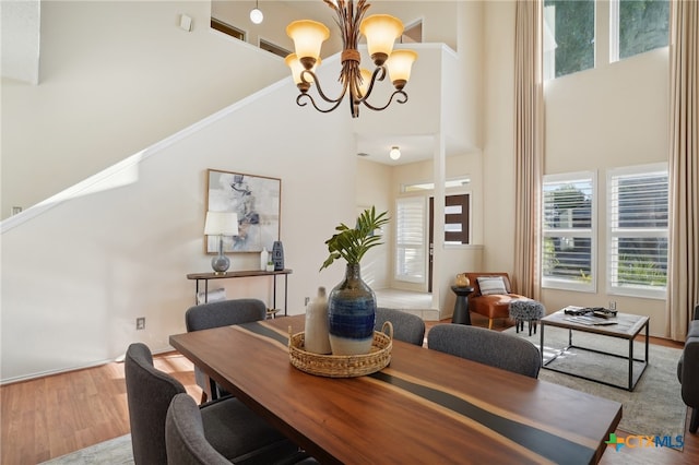 dining space featuring light hardwood / wood-style floors, a high ceiling, and a chandelier