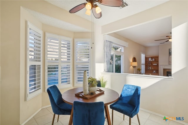 tiled dining room with ceiling fan and a textured ceiling