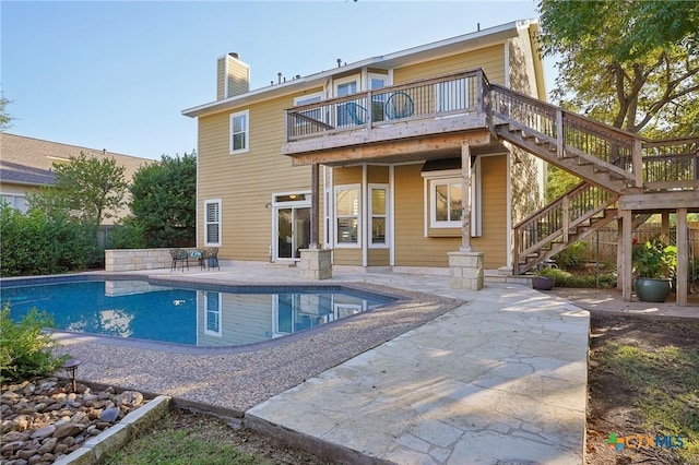 rear view of house featuring a patio and a fenced in pool