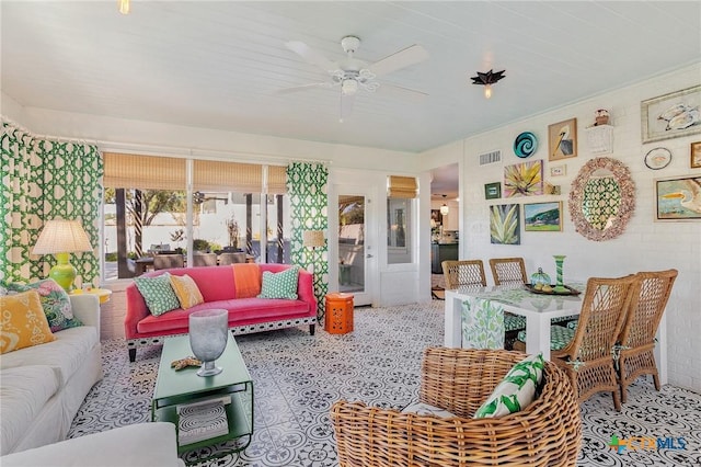 living room with ceiling fan and brick wall