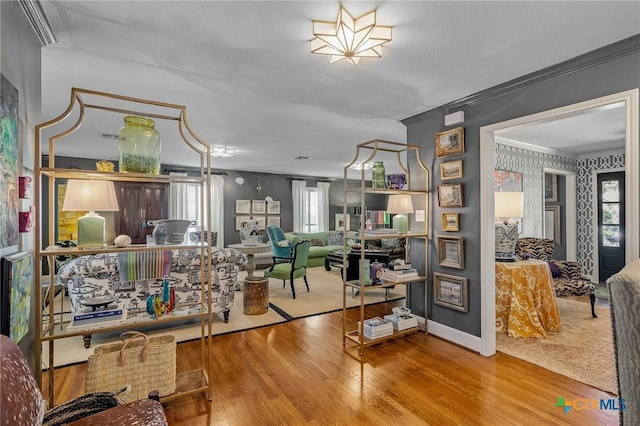 living area with crown molding and wood-type flooring