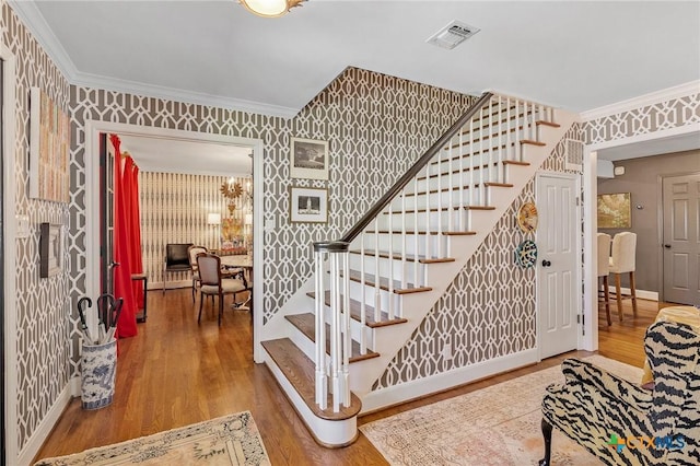 staircase with hardwood / wood-style floors and ornamental molding