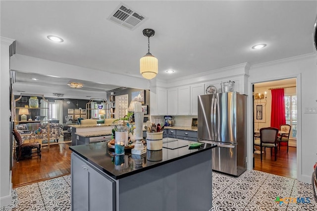 kitchen featuring a healthy amount of sunlight, white cabinetry, hanging light fixtures, and stainless steel refrigerator