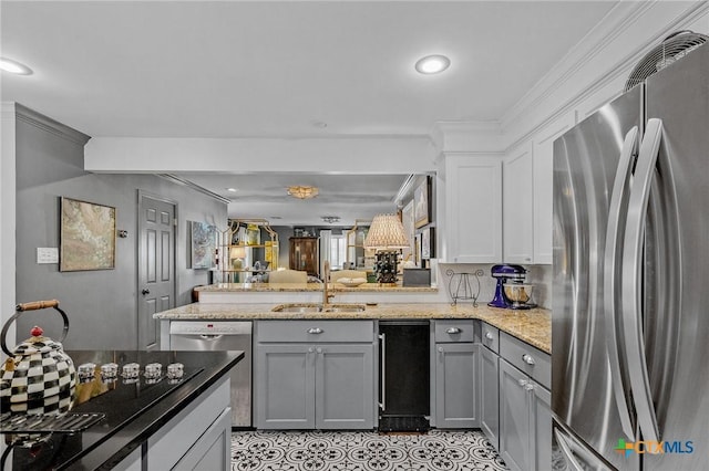 kitchen with light stone counters, stainless steel appliances, crown molding, sink, and gray cabinets