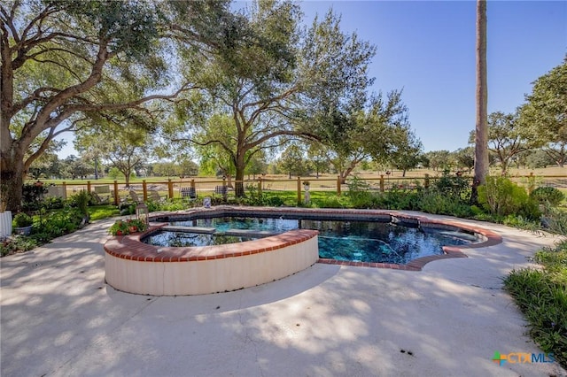 view of pool featuring a patio area, a rural view, and an in ground hot tub