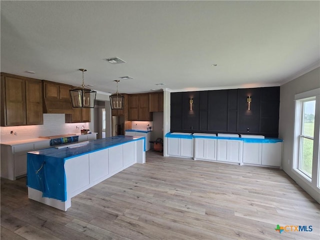 8186 S Lone Star Pkwy, Moody, TX 76657 - kitchen featuring light wood finished floors, a center island, visible vents, backsplash, and ornamental molding