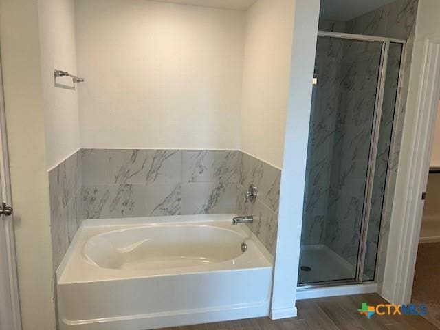 full bathroom with a bath, wood finished floors, and a stall shower