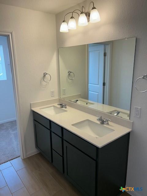 bathroom with a sink, baseboards, and double vanity