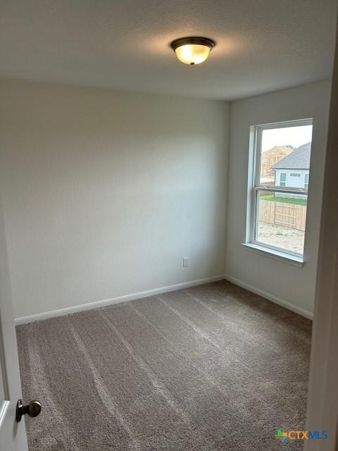 carpeted spare room featuring baseboards and a textured ceiling