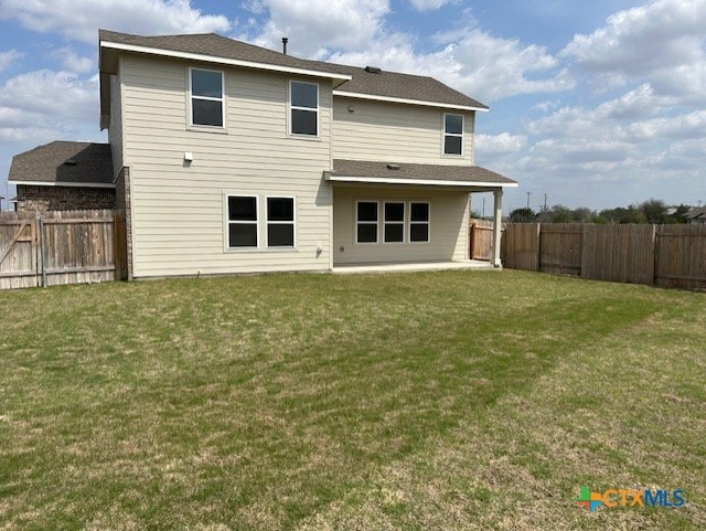 rear view of house with a yard and a fenced backyard