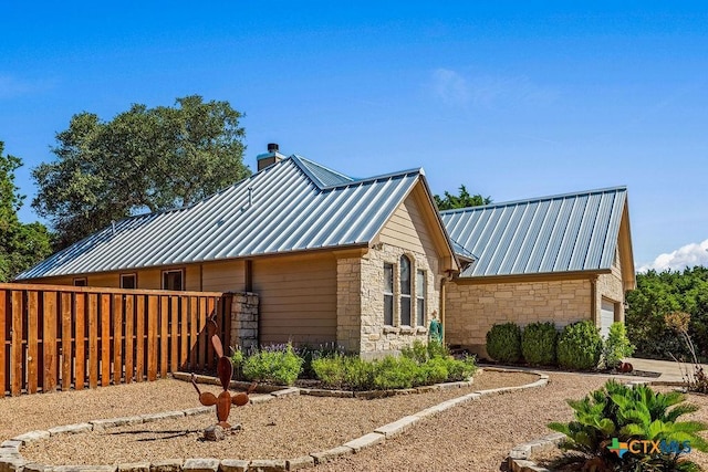 10 Long Bow Ln, Wimberley, TX 78676 - view of home's exterior featuring stone siding, a standing seam roof, a chimney, and a metal roof