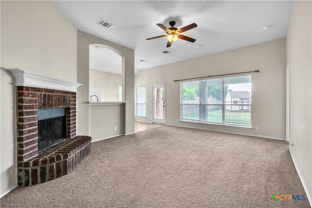 unfurnished living room with a brick fireplace, plenty of natural light, and carpet floors