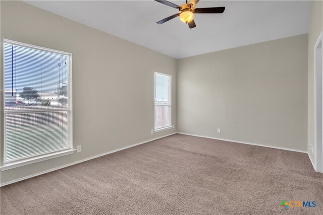 carpeted spare room featuring ceiling fan and plenty of natural light